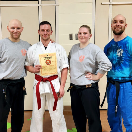 Masters Michael and Sarah Buzby, along with Instructor Anthony Pierce pose with a student who just passed his red belt test.